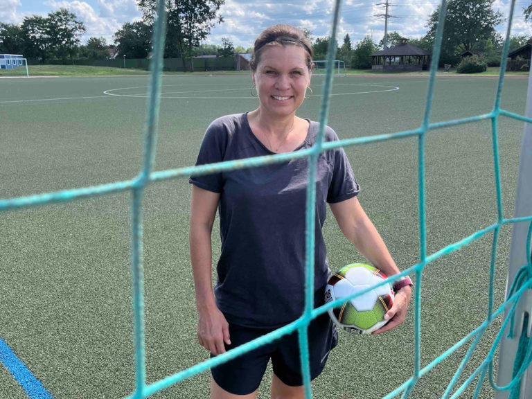 Louise Hansen auf einem Sportplatz mit einem Ball unter dem Arm.